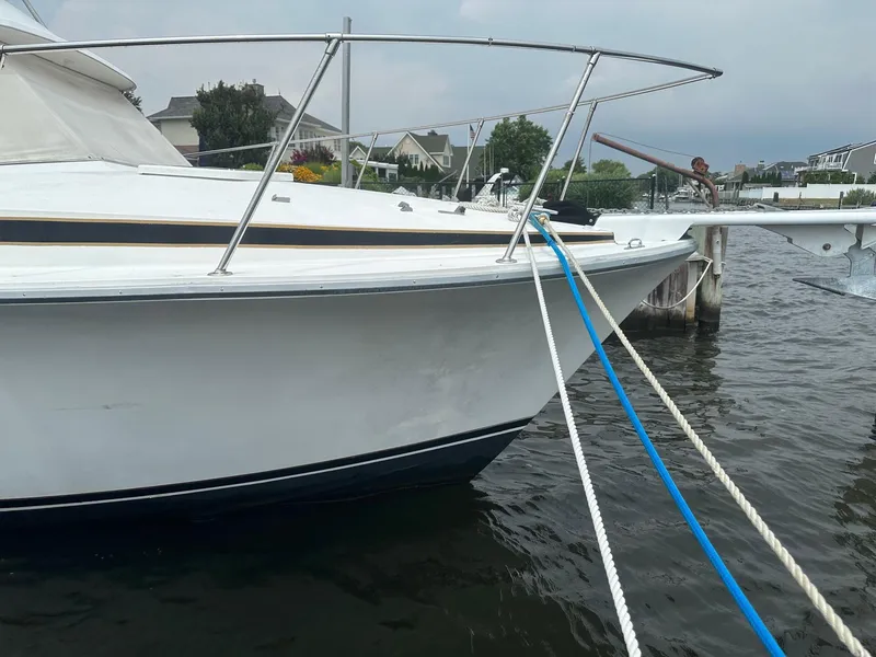 Slide: The Image of 1978 Bertram 33 Convertible boat docked with ropes, calm water, and residential background. - 6
