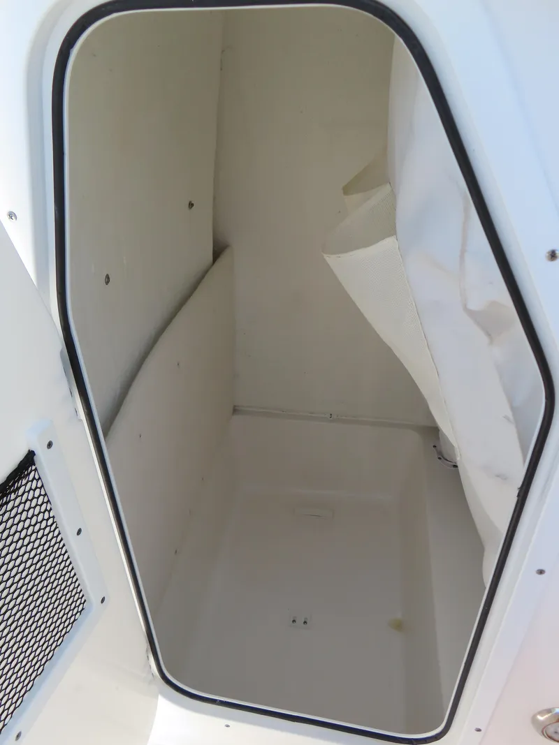 Slide: The Image of Storage compartment inside 2020 Sea Hunt Ultra 234 boat, featuring white interior and netted pocket. - 20