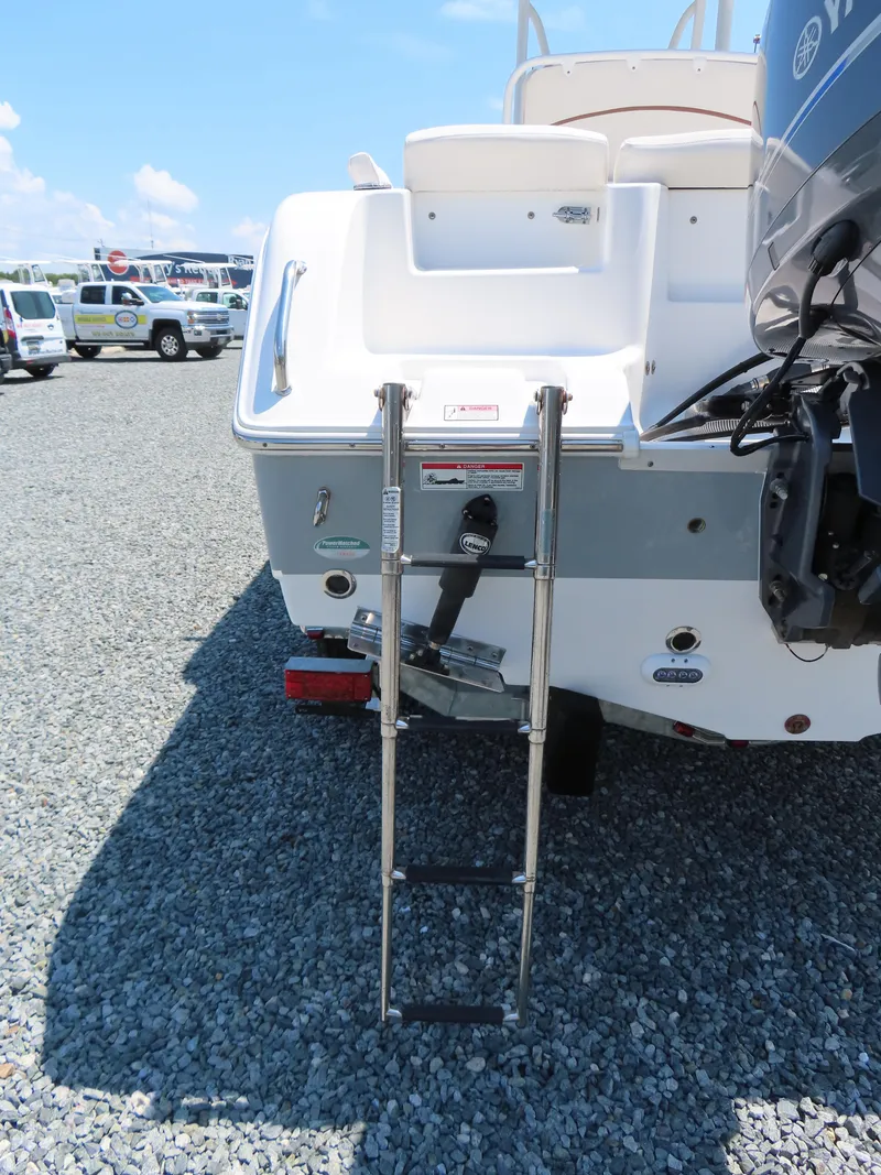 Slide: The Image of 2020 Sea Hunt Ultra 234 boat with ladder and outboard motor on gravel. - 6