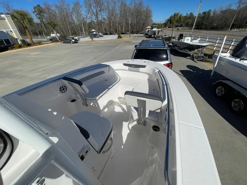 Slide: The Image of 2023 Robalo R202 Explorer boat interior with seating, parked near vehicles and trees. - 7