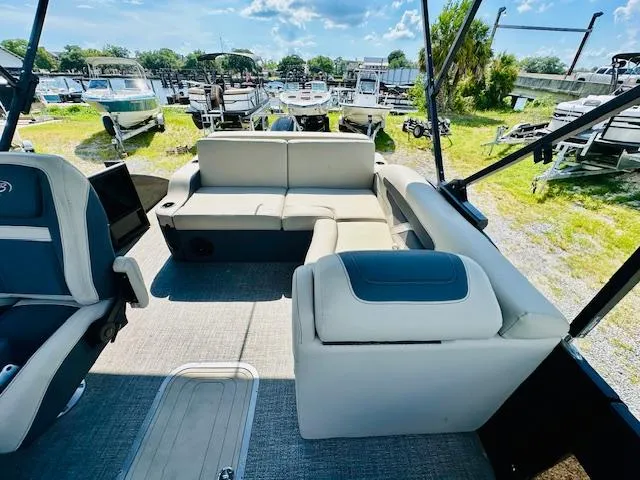 Slide: The Image of 2022 Barletta C24U pontoon boat interior with plush seating, docked at a marina. - 16