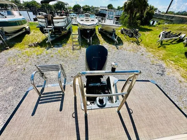Slide: The Image of 2022 Barletta C24U pontoon boat with motor, docked among other boats on a sunny day. - 19