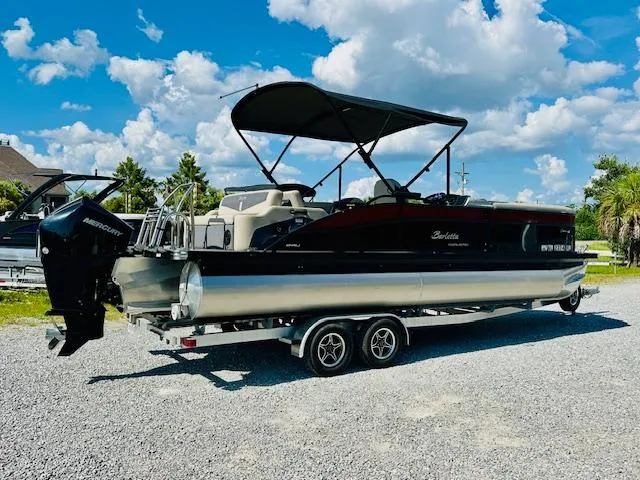 Slide: The Image of 2022 Barletta C24U pontoon boat on trailer under blue sky. - 2