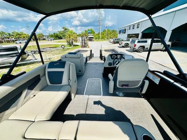 Slide: The Image of 2022 Barletta C24U pontoon boat interior with seating and steering wheel, parked outdoors. - 21