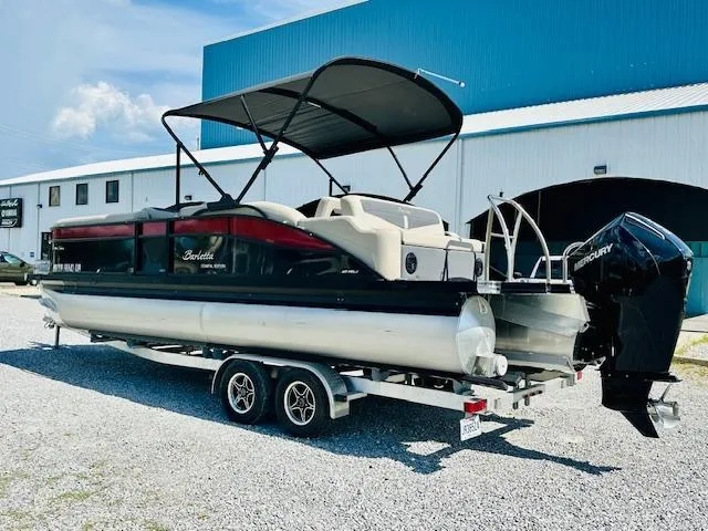 Slide: The Image of 2022 Barletta C24U pontoon boat on trailer, parked outside a blue and white building. - 4