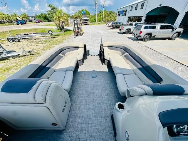 Slide: The Image of 2022 Barletta C24U pontoon boat with spacious seating, parked outdoors near a dealership. - 9