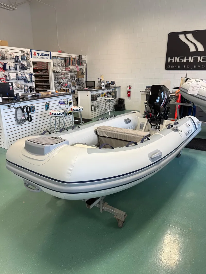 Slide: The Image of 2024 Highfield CL360 inflatable boat displayed in a showroom with Suzuki accessories. - 3