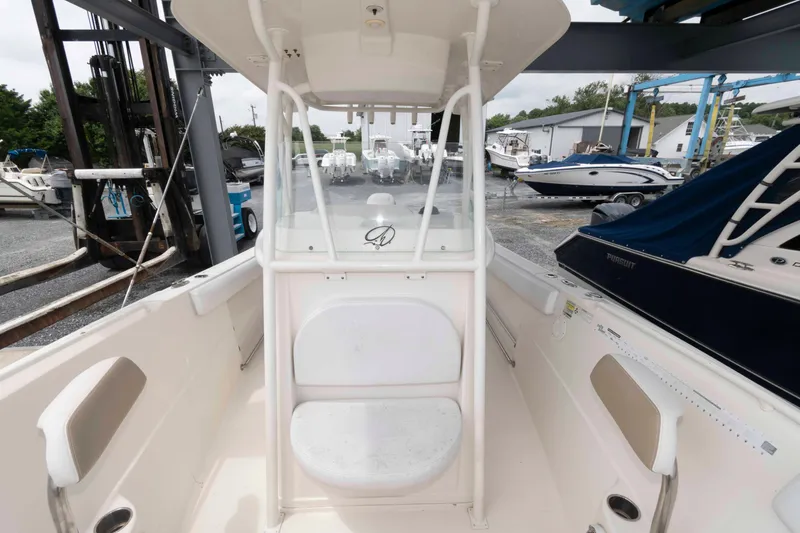 Slide: The Image of 2016 Sailfish 240 CC boat interior, featuring helm station and seating, docked at a marina. - 10