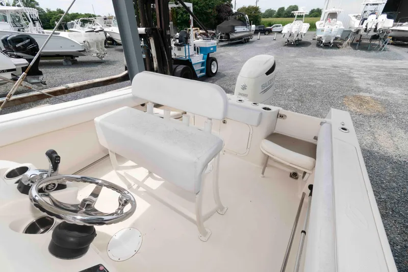 Slide: The Image of 2016 Sailfish 240 CC boat interior with steering wheel and seating, parked in a marina. - 11