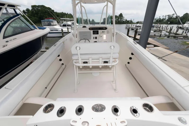 Slide: The Image of 2016 Sailfish 240 CC boat interior with helm, seating, and rod holders at a marina. - 6