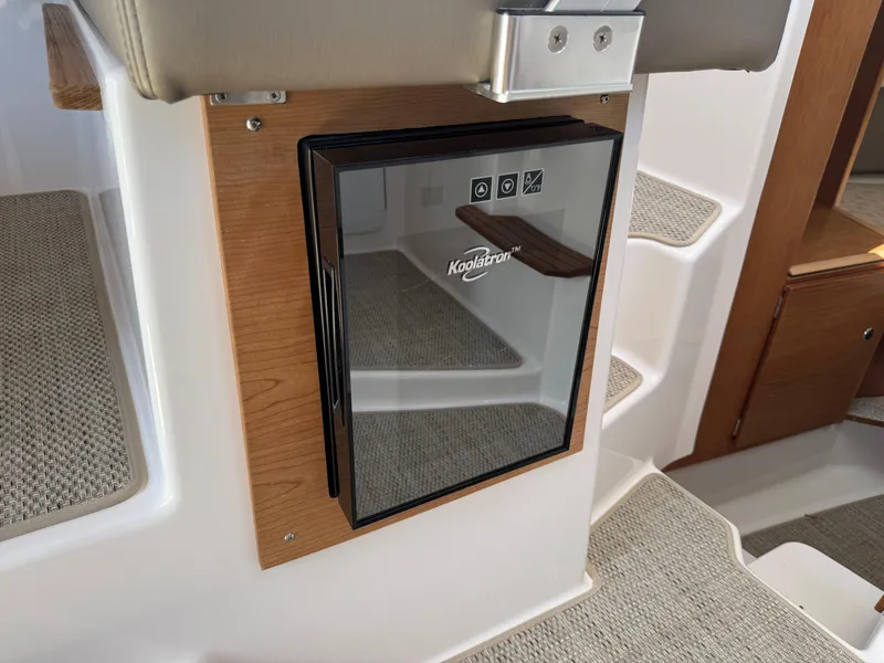 Slide: The Image of Koolatron fridge in 2025 Cutwater C-288 Coupe boat interior, featuring wood accents and carpeted steps. - 23