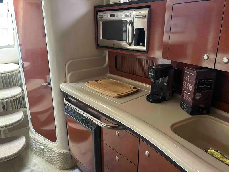 Slide: The Image of 2005 Sea Ray 320 Sundancer galley with microwave, coffee maker, and wooden cutting board. - 12