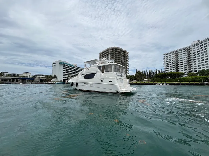 Slide: The Image of 2000 Silverton 453 Motor Yacht cruising near waterfront buildings under cloudy skies. - 6