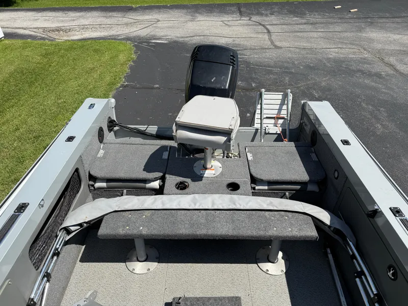 Slide: The Image of 2005 Lund 1700 Fisherman boat interior with seating and motor, parked on pavement. - 6