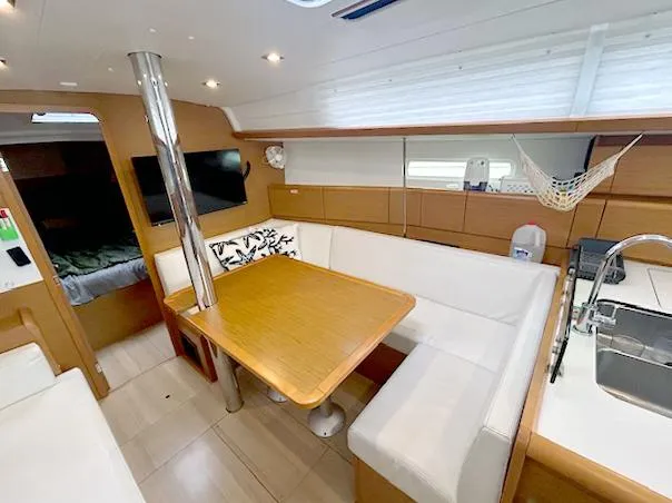 Slide: The Image of 2018 Jeanneau Sun Odyssey 389 interior with dining area, white seating, and modern kitchen amenities. - 9