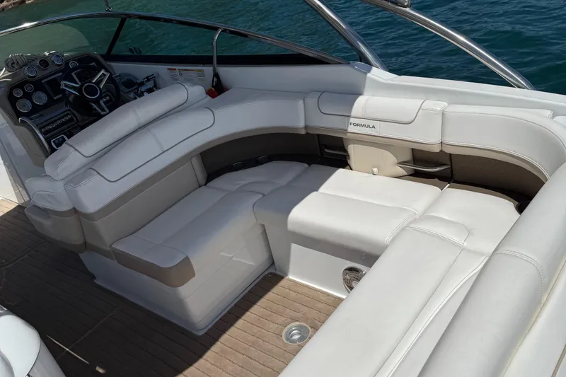 Slide: The Image of 2013 Formula 290 Bowrider interior with white seating and sleek dashboard, on water. - 12