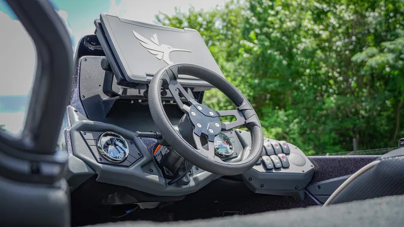 Slide: The Image of 2026 Skeeter ZXE 20 boat dashboard with steering wheel and control panel, surrounded by greenery. - 17