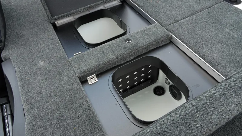 Slide: The Image of 2026 Skeeter ZXE 20 boat storage compartments with gray carpeted lids. - 27