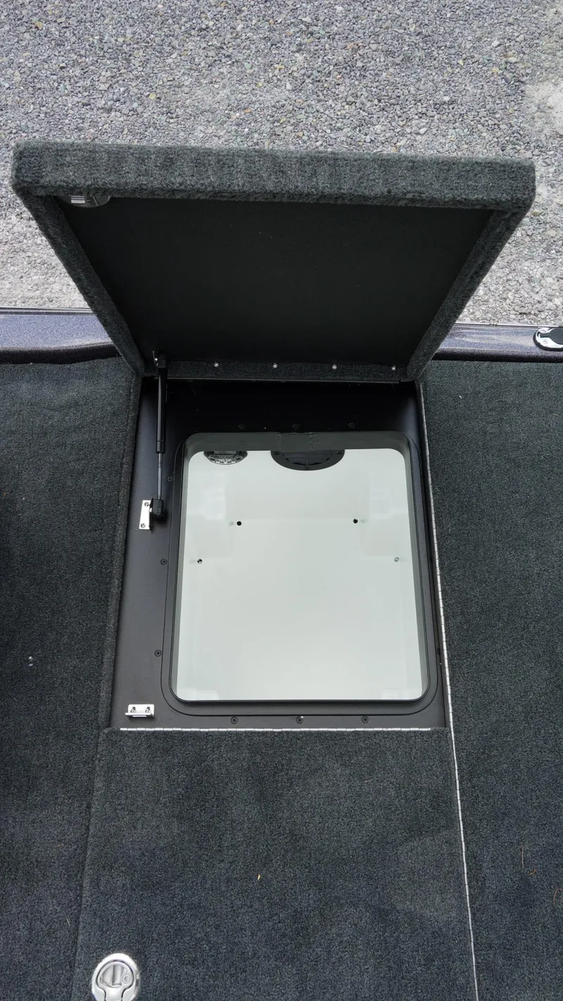 Slide: The Image of 2026 Skeeter ZXE 20 boat storage compartment with open lid on carpeted deck. - 29