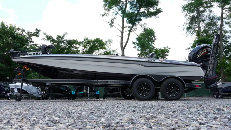 Slide: The Image of 2026 Skeeter ZXE 20 boat on trailer, parked on gravel, surrounded by trees. - 46