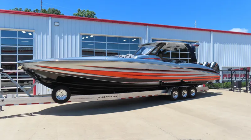 Slide: The Image of 2020 MTI 42V powerboat with orange and black design on a trailer outside a building. - 1