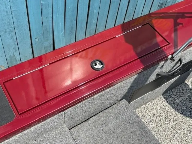 Slide: The Image of 2015 Tracker Targa V-18 Combo boat with red storage compartment and blue wooden background. - 26