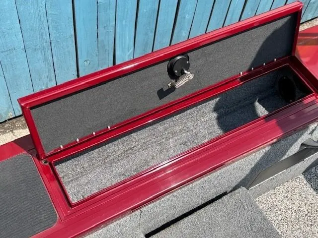 Slide: The Image of Open storage compartment on 2015 Tracker Targa V-18 Combo boat, red exterior, blue background. - 27