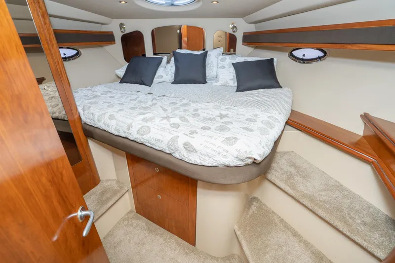 Slide: The Image of Luxurious cabin interior of 2005 Cruisers Yachts 370 Express with cozy bedding and elegant wood finishes. - 29