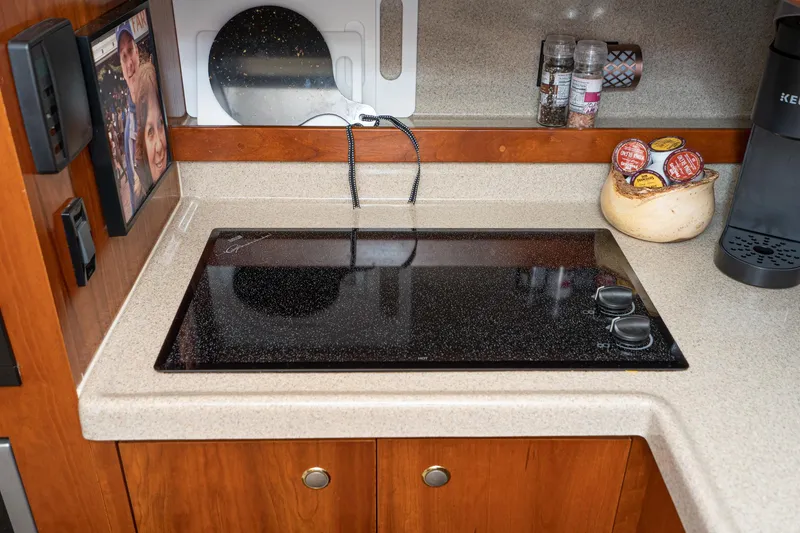 Slide: The Image of 2005 Cruisers Yachts 370 Express kitchen with stovetop, coffee maker, and spice rack. - 32