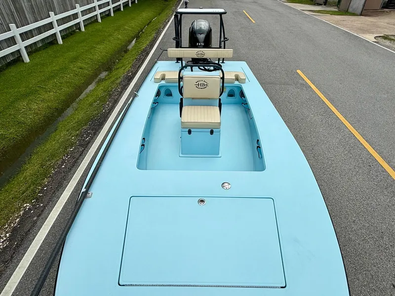 Slide: The Image of 2021 Hell's Bay Marquesa boat on road, light blue deck, white fence background. - 14