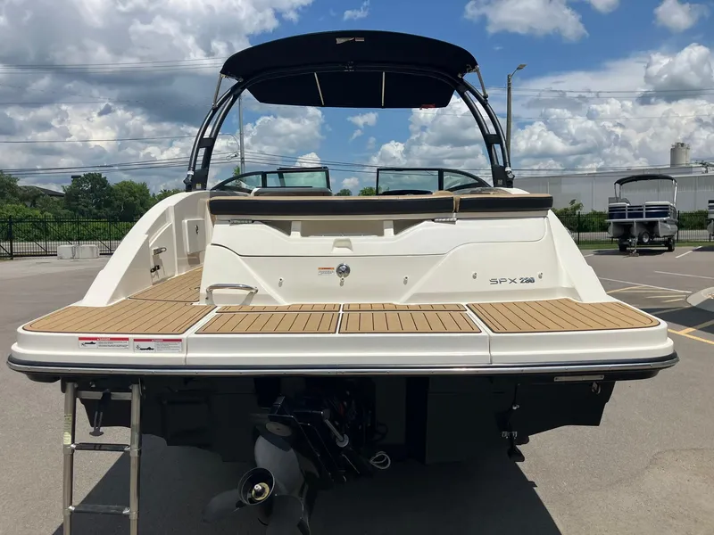 Slide: The Image of 2023 Sea Ray SPX 230 boat, rear view, showcasing swim platform and ladder under a blue sky. - 3