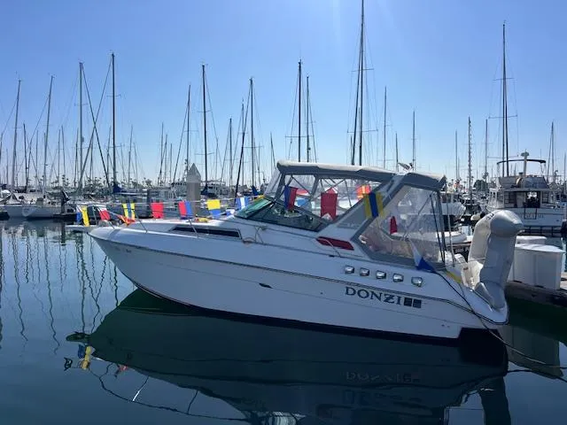 The Image of 1990 Donzi 300 Levante boat docked in a marina, adorned with colorful flags. - 1