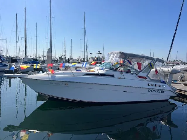 Slide: The Image of 1990 Donzi 300 Levante boat docked, adorned with colorful flags, in a marina setting. - 4