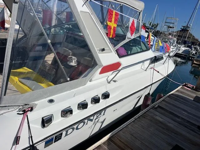 Slide: The Image of 1990 Donzi 300 Levante boat docked, adorned with colorful flags, in a marina setting. - 7