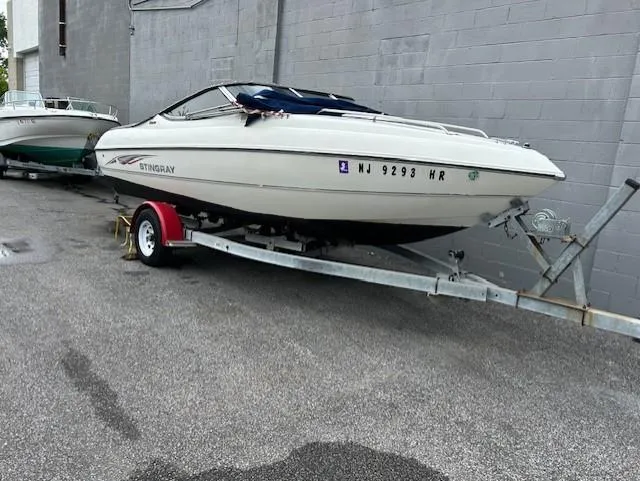 Slide: The Image of 2004 Stingray 220 CS boat on trailer, parked beside a gray wall. - 4