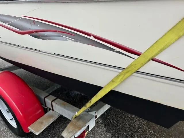 Slide: The Image of 2004 Stingray 220 CS boat on trailer with red and gray graphics, secured by yellow strap. - 7