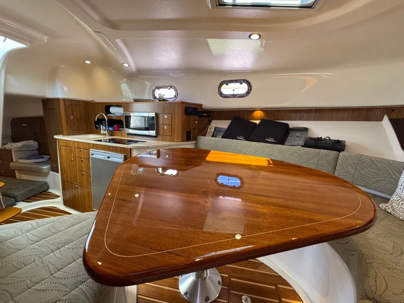 Slide: The Image of Luxurious interior of a 2014 Pursuit 345 OS boat with polished wood table and modern kitchen. - 10