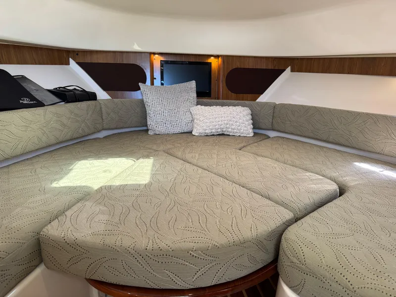 Slide: The Image of 2014 Pursuit 345 OS cabin interior with cushioned seating and decorative pillows. - 13