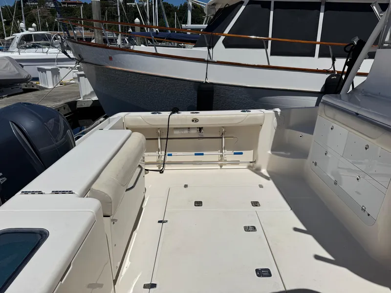 Slide: The Image of 2014 Pursuit 345 OS boat interior with seating and storage, docked at a marina. - 28