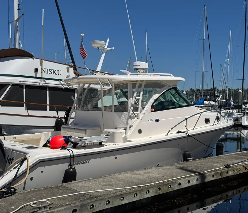 Slide: The Image of 2014 Pursuit 345 OS boat docked at marina under clear blue sky. - 34