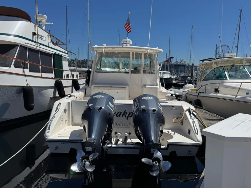 Slide: The Image of 2014 Pursuit 345 OS boat docked with twin outboard engines in a marina. - 35