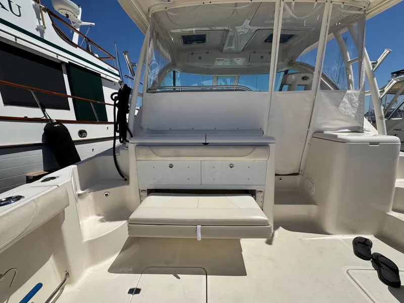 Slide: The Image of 2014 Pursuit 345 OS boat interior with seating and storage, docked beside another vessel. - 7