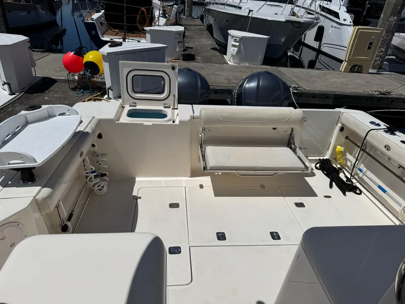 Slide: The Image of 2014 Pursuit 345 OS boat interior with seating and storage at a marina. - 8