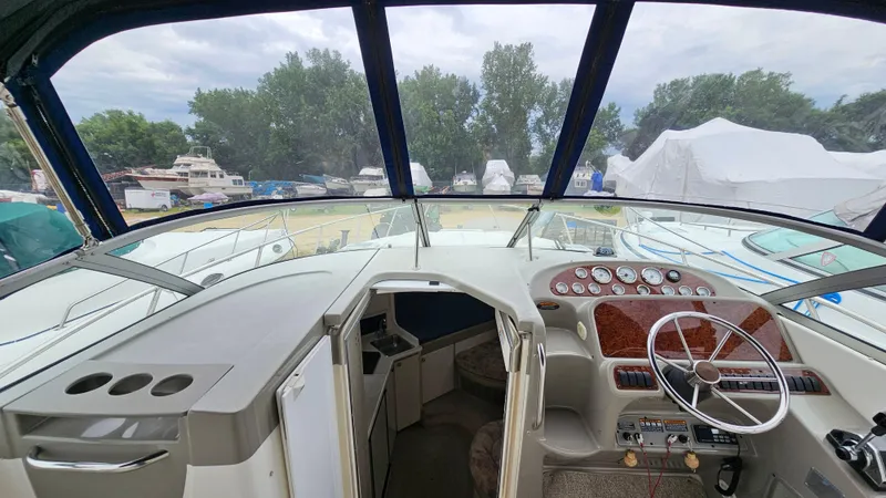Slide: The Image of 1999 Bayliner 3055 Ciera boat cockpit with steering wheel and dashboard, surrounded by other boats. - 10