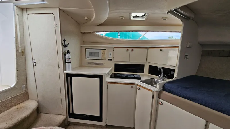 Slide: The Image of 1999 Bayliner 3055 Ciera interior with kitchenette, microwave, sink, and storage cabinets. - 14