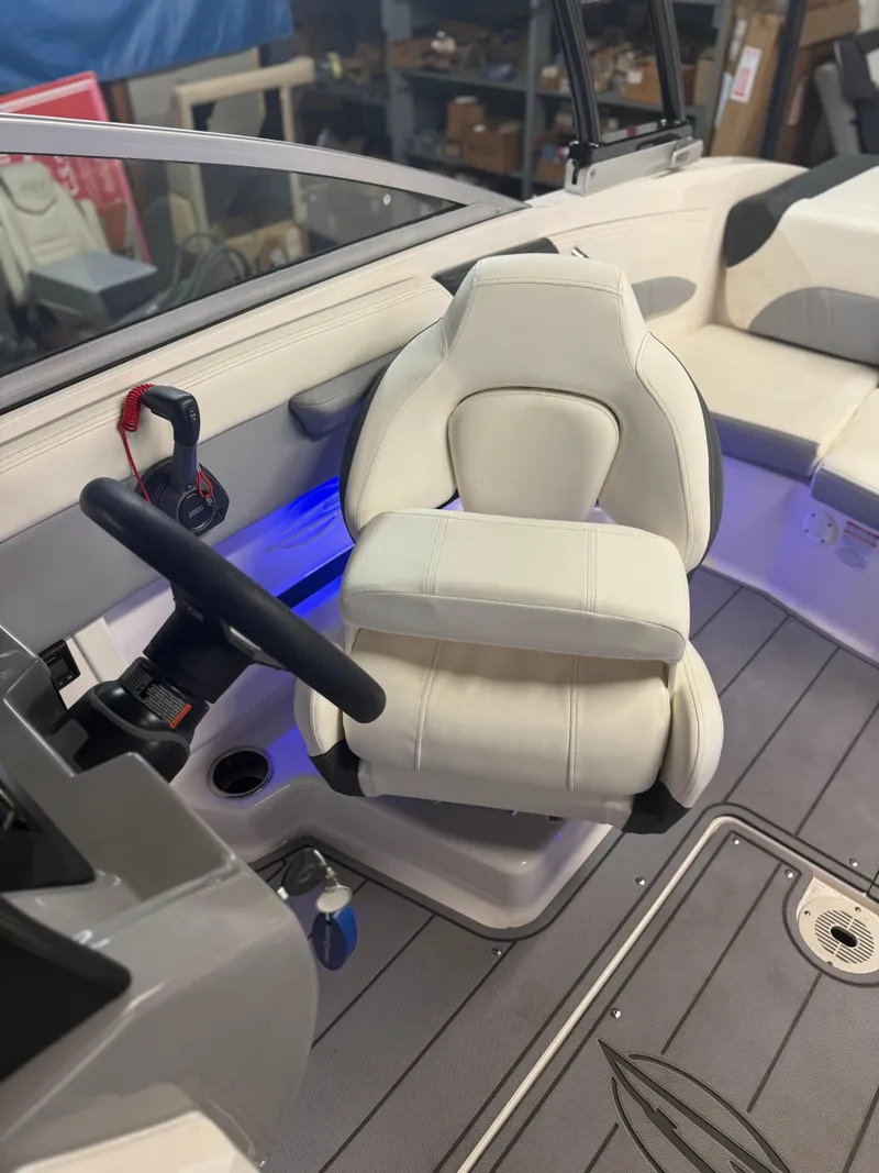 Slide: The Image of 2023 Chaparral 21 Surf boat interior with white captain's seat and blue accent lighting. - 10