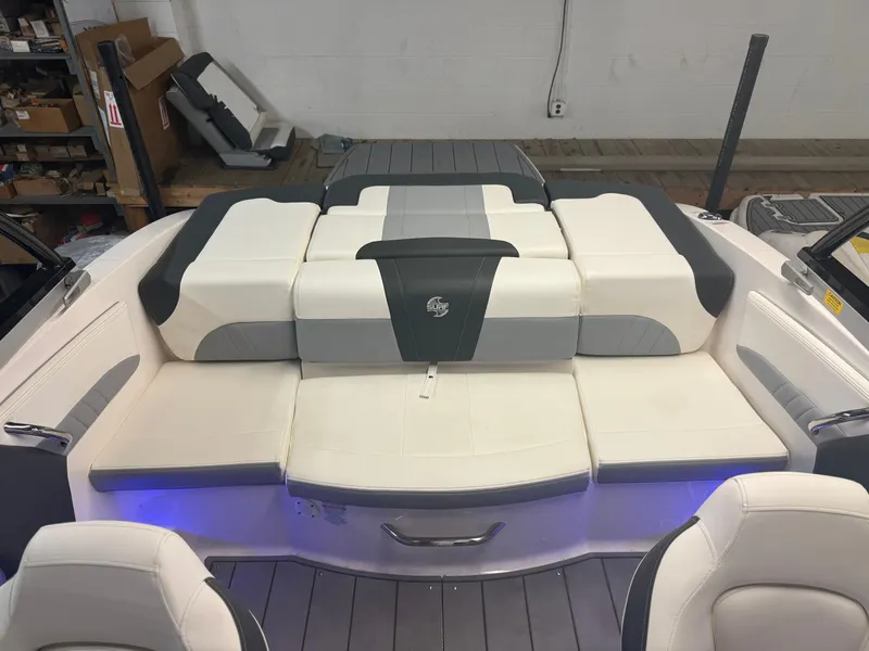 Slide: The Image of 2023 Chaparral 21 Surf boat interior with white and gray seating, illuminated by blue lights. - 14