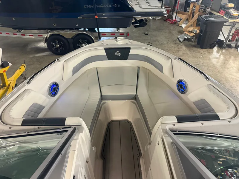 Slide: The Image of 2023 Chaparral 21 Surf boat interior with gray seating and blue speakers in a workshop. - 3
