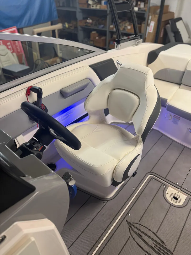 Slide: The Image of 2023 Chaparral 21 Surf boat interior with white captain's seat and blue accent lighting. - 9