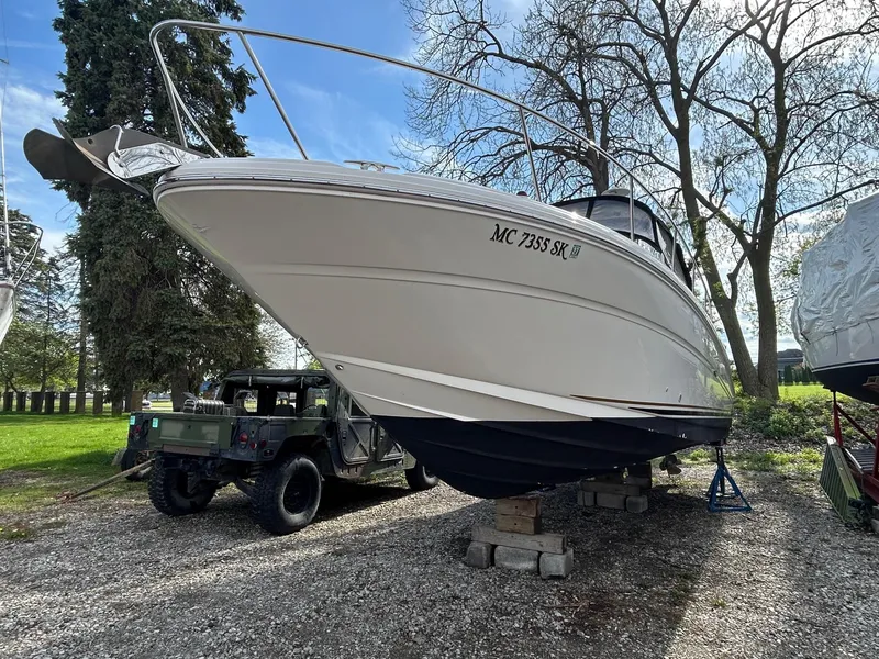 Slide: The Image of 2002 Sea Ray 300 Sundancer boat on blocks, parked outdoors near trees. - 1